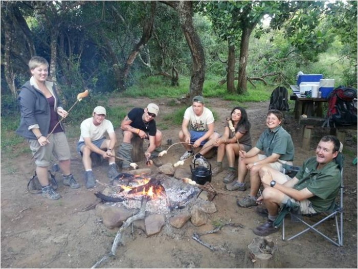 volunteers and the Shamwari team share food around a campfire