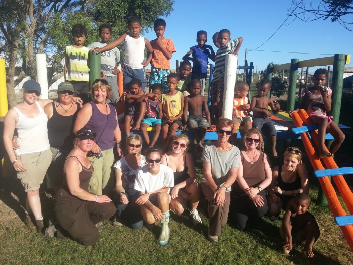 volunteers pose with members of the local community after building a jungle gym