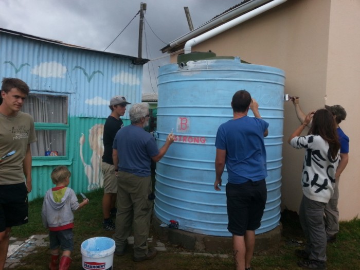 Volunteers use their creativity to paint a water tank in the local community