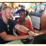 A volunteer shows a local boy how to use a laptop