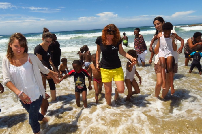 Volunteers play in the sea with local school children