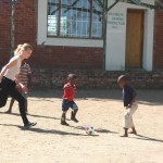 A volunteer kicking a ball with local school children