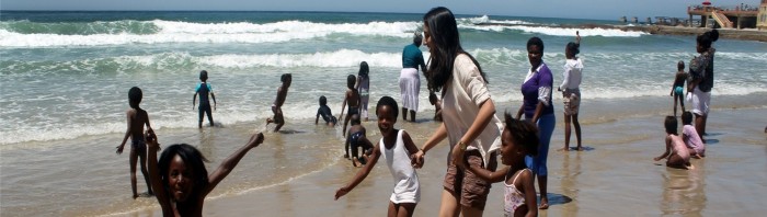 Volunteers play in the sea with local school children