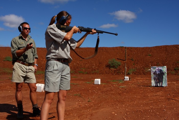 A volunteer practices her shooting as a game ranger watches on
