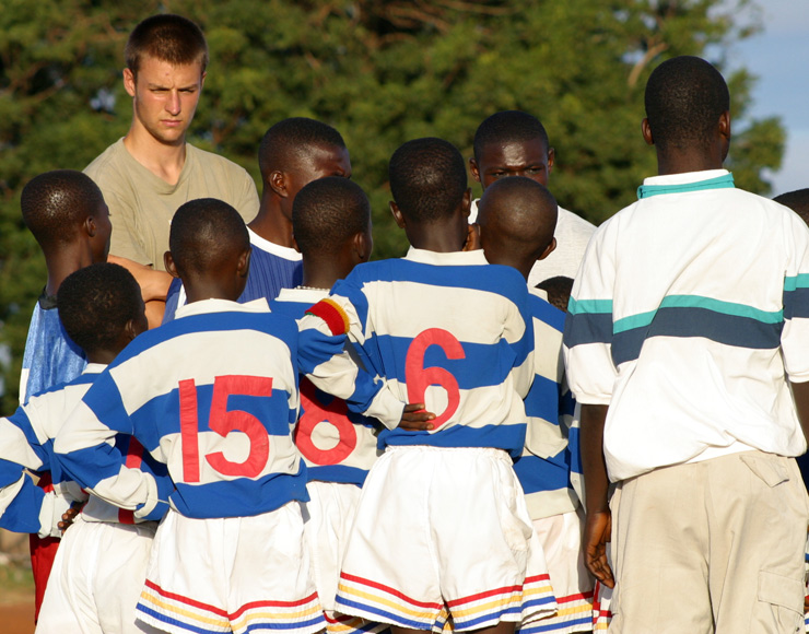 Local football players discuss tactics as a volunteer watches on