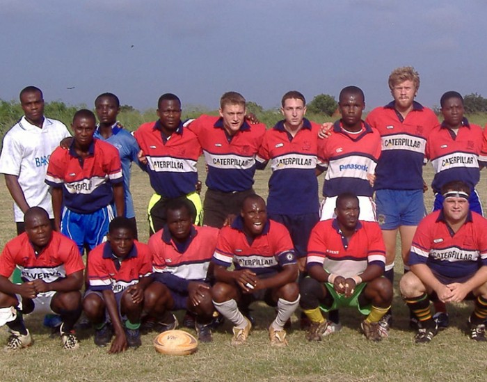 Rugby coaching volunteers pose in a team picture with members of the community