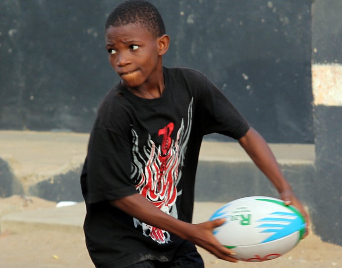 A young boy holding a rugby ball