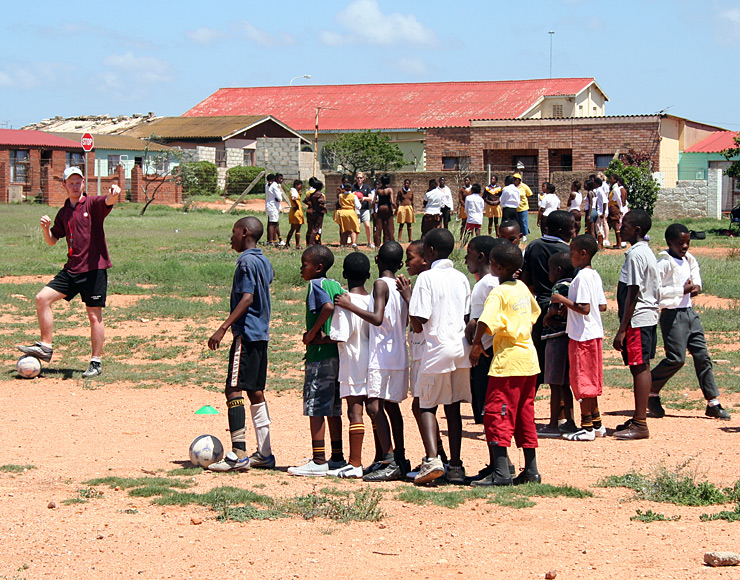 A volunteer training kids on how to pass a football